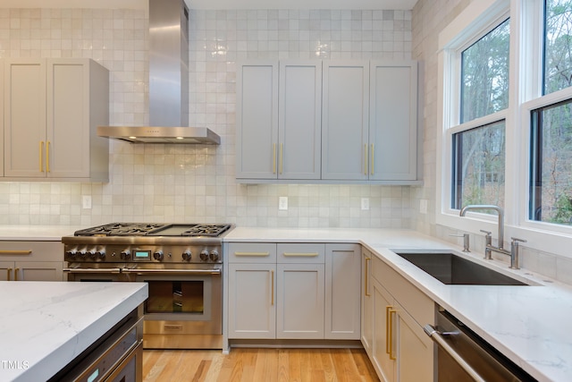 kitchen featuring appliances with stainless steel finishes, sink, decorative backsplash, and wall chimney range hood