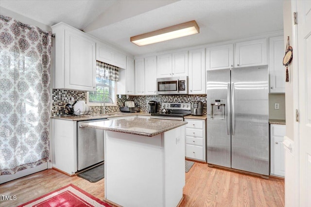 kitchen featuring light wood-type flooring, stainless steel appliances, sink, white cabinetry, and a kitchen island