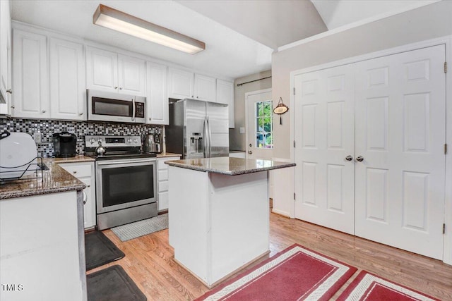 kitchen featuring stainless steel appliances, white cabinetry, a kitchen island, and dark stone countertops