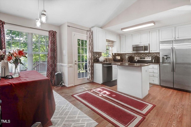 kitchen featuring pendant lighting, a center island, lofted ceiling, white cabinetry, and stainless steel appliances