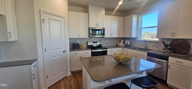 kitchen with stainless steel appliances, sink, white cabinets, a center island, and a breakfast bar area