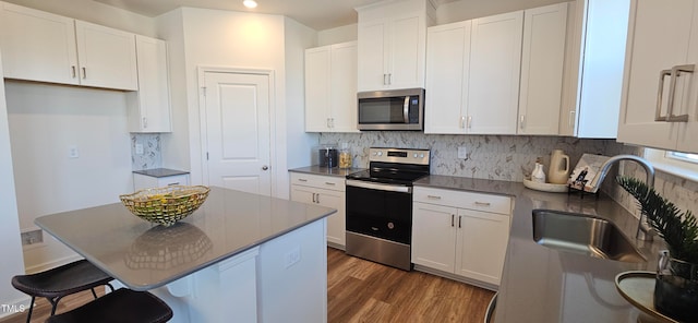 kitchen featuring sink, dark wood-type flooring, decorative backsplash, white cabinets, and appliances with stainless steel finishes