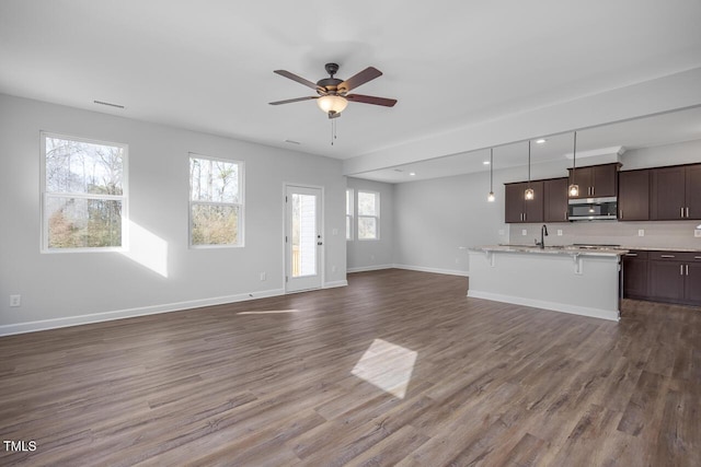 unfurnished living room featuring hardwood / wood-style flooring, sink, and ceiling fan