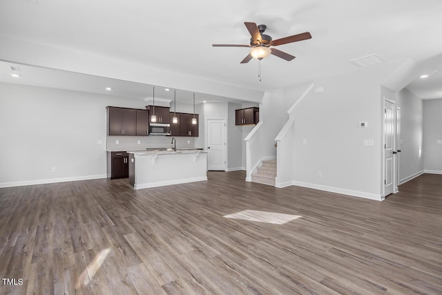 unfurnished living room with dark hardwood / wood-style flooring, sink, and ceiling fan