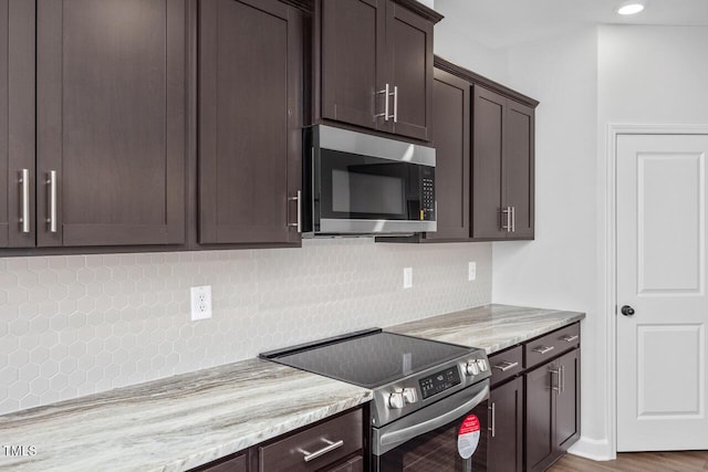 kitchen with hardwood / wood-style floors, stainless steel appliances, dark brown cabinetry, tasteful backsplash, and light stone countertops