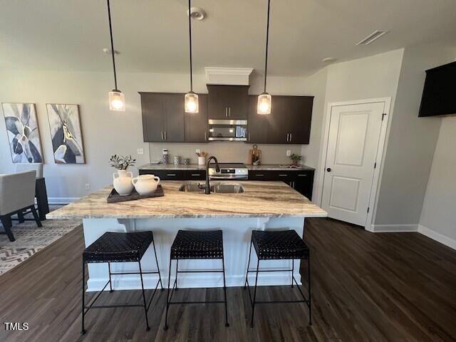 kitchen with sink, decorative light fixtures, and an island with sink