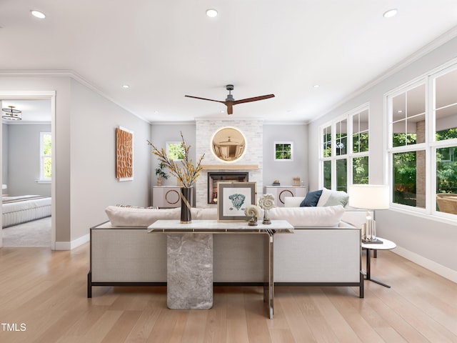 living room with a large fireplace, ceiling fan, crown molding, and light hardwood / wood-style flooring