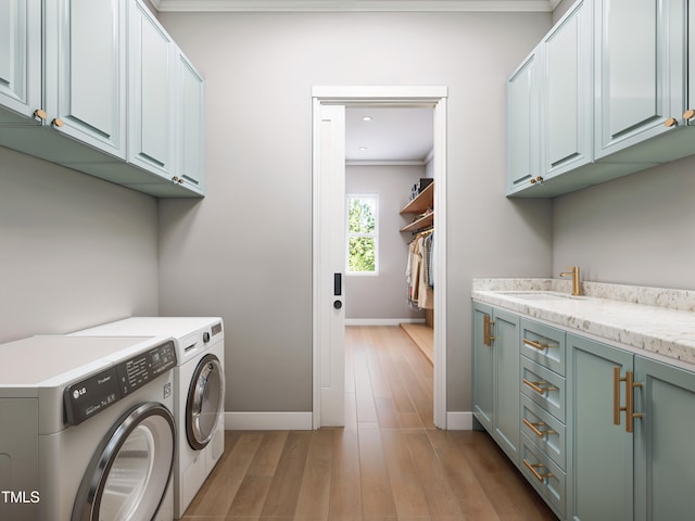 clothes washing area featuring light wood-type flooring, independent washer and dryer, cabinets, and sink