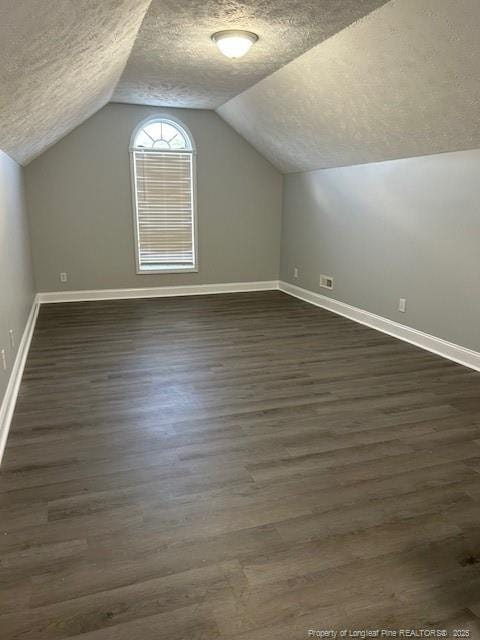 bonus room featuring vaulted ceiling, dark hardwood / wood-style flooring, and a textured ceiling