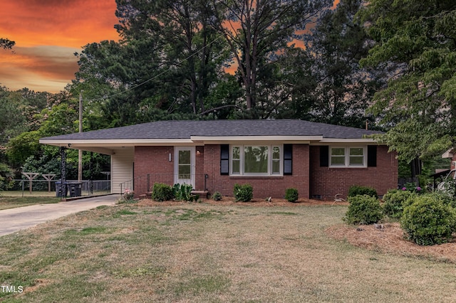 view of front of home with a carport and a lawn