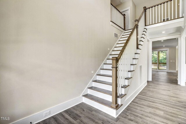 stairway featuring a high ceiling and hardwood / wood-style floors