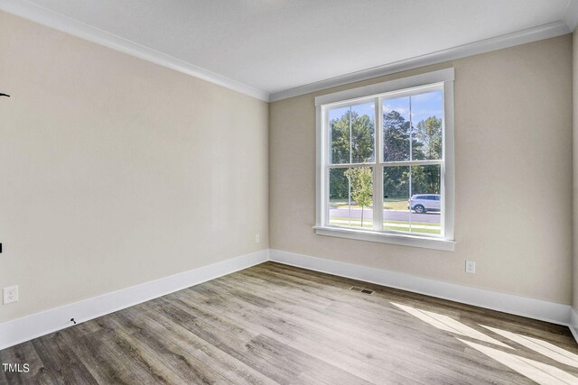 empty room featuring light wood-type flooring and ornamental molding