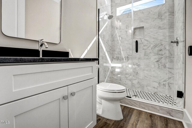 bathroom featuring a shower with door, hardwood / wood-style flooring, vanity, and toilet