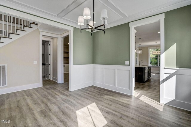 unfurnished dining area with wood-type flooring, crown molding, an inviting chandelier, and sink