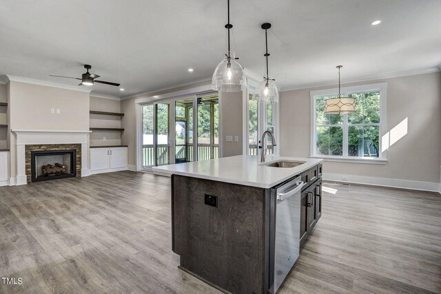 kitchen featuring an island with sink, a fireplace, sink, and a wealth of natural light