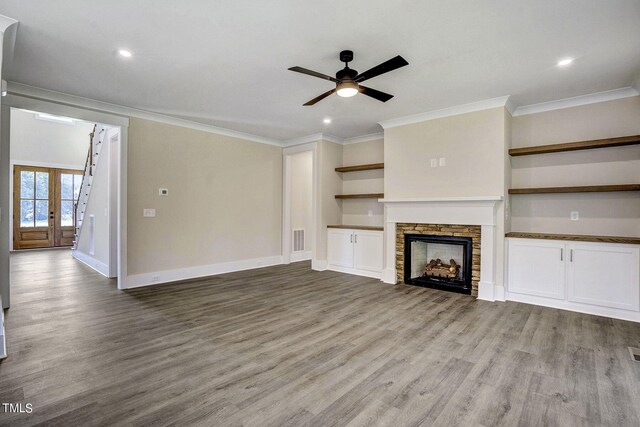 unfurnished living room with light wood-type flooring, a fireplace, ornamental molding, ceiling fan, and french doors