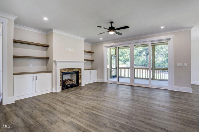 unfurnished living room with ceiling fan, a fireplace, crown molding, and dark wood-type flooring