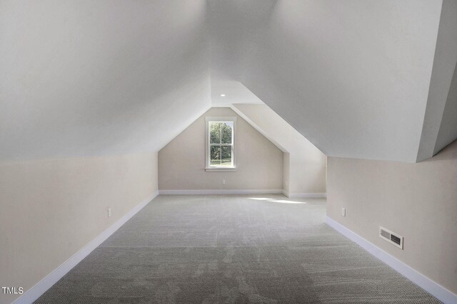 bonus room with light colored carpet and vaulted ceiling