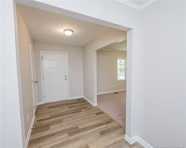 interior space featuring a textured ceiling, hardwood / wood-style flooring, and crown molding