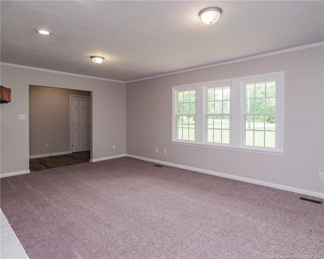 empty room featuring dark carpet, a textured ceiling, and ornamental molding