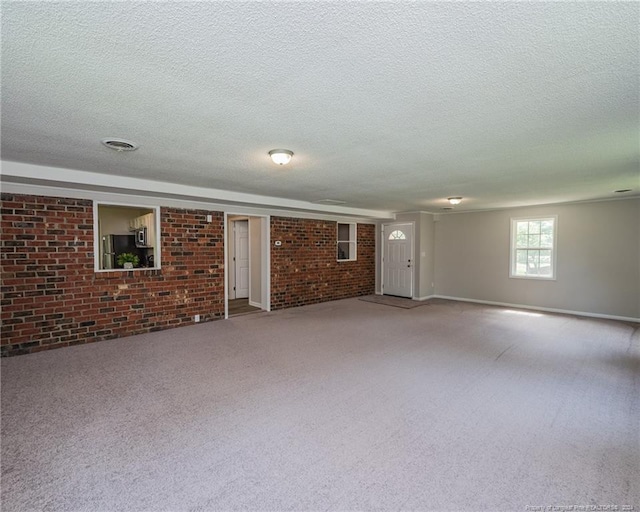 interior space with carpet floors, brick wall, and a textured ceiling