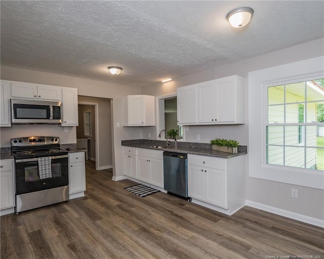 kitchen featuring white cabinets, sink, dark stone countertops, appliances with stainless steel finishes, and dark hardwood / wood-style flooring