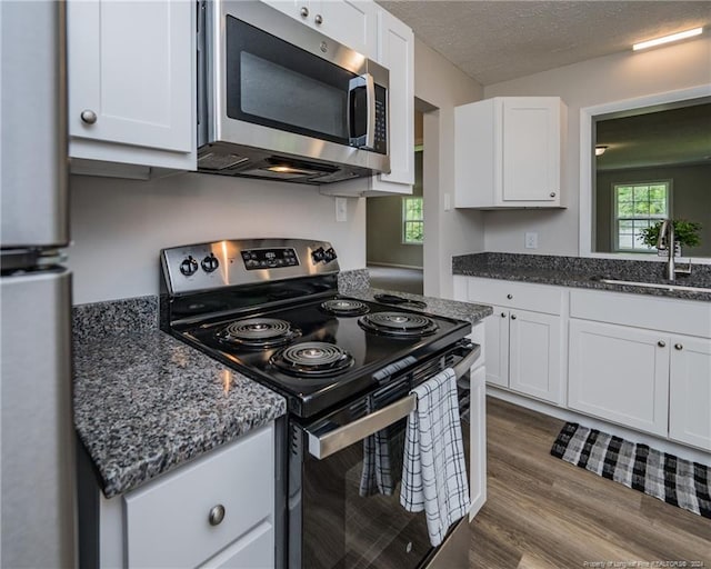 kitchen featuring hardwood / wood-style floors, white cabinets, sink, a textured ceiling, and appliances with stainless steel finishes