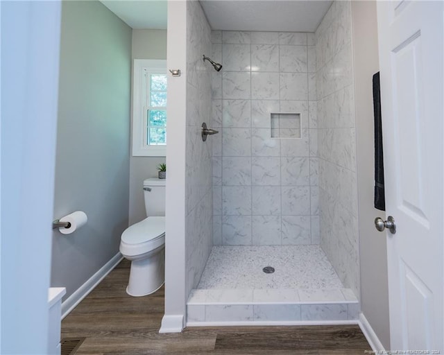 bathroom featuring tiled shower, hardwood / wood-style flooring, and toilet