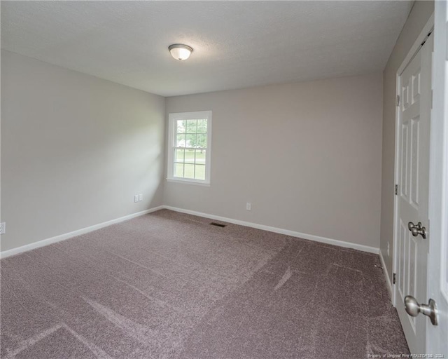 carpeted empty room featuring a textured ceiling