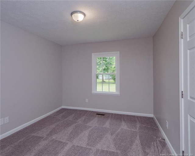 spare room featuring carpet flooring and a textured ceiling