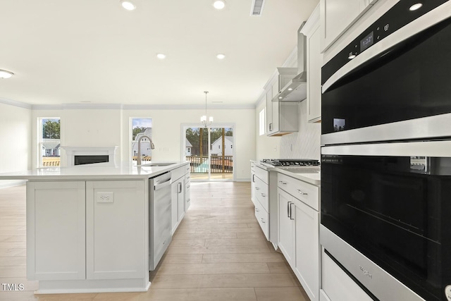 kitchen with stainless steel appliances, white cabinetry, sink, and a center island with sink