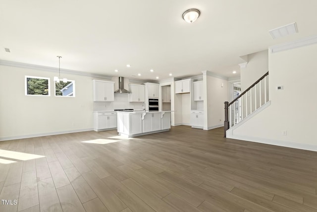 unfurnished living room with hardwood / wood-style floors, crown molding, and a notable chandelier