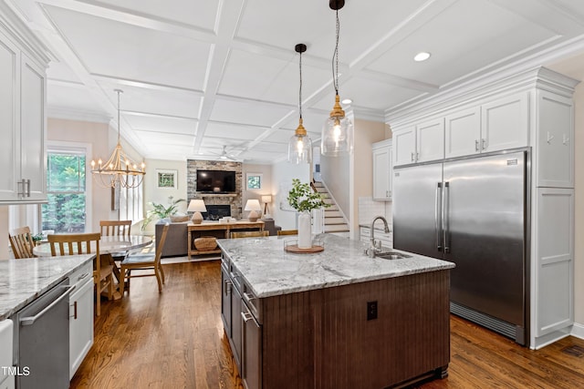 3209 Bryant Falls Ct, Raleigh, NC 27613 - kitchen with a sink, stainless steel appliances, a fireplace, white cabinets, and coffered ceiling