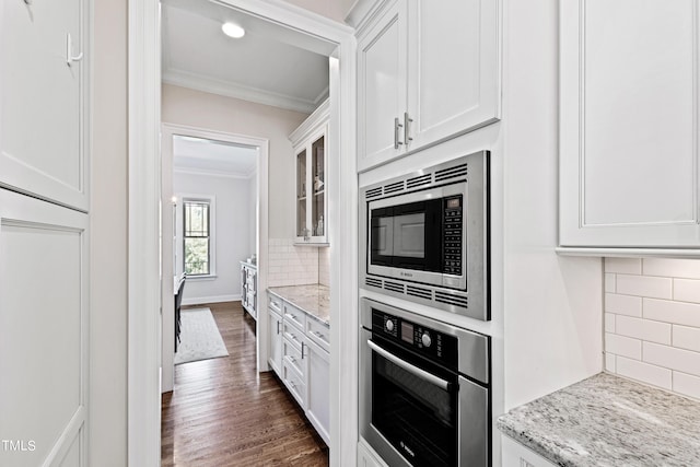 3209 Bryant Falls Ct, Raleigh, NC 27613 - kitchen featuring appliances with stainless steel finishes, crown molding, white cabinetry, dark wood-style floors, and backsplash