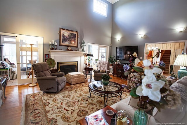 living room with a high ceiling, a tile fireplace, and light wood-type flooring