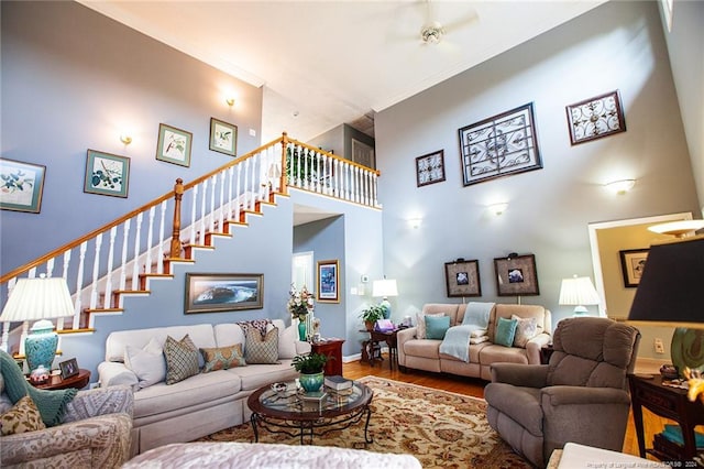 living room featuring hardwood / wood-style flooring, ornamental molding, and a high ceiling