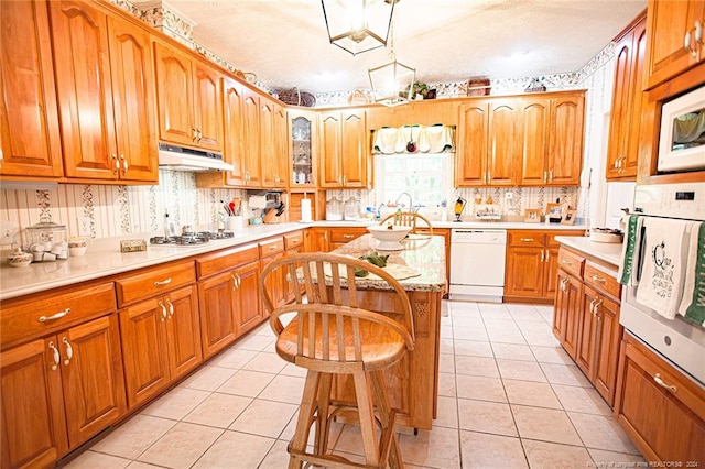 kitchen featuring tasteful backsplash, a center island, light tile patterned floors, and white appliances