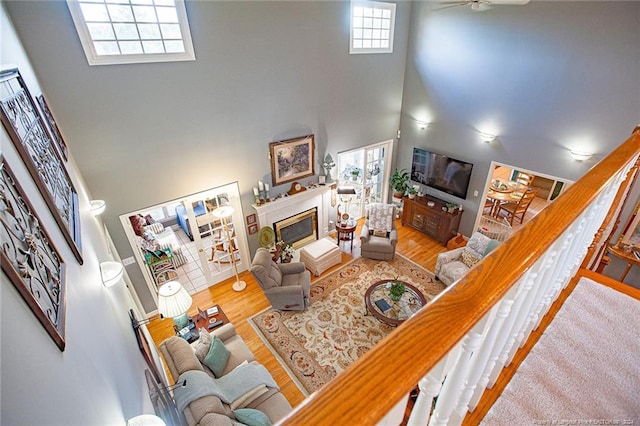 living room with hardwood / wood-style floors, a towering ceiling, and ceiling fan