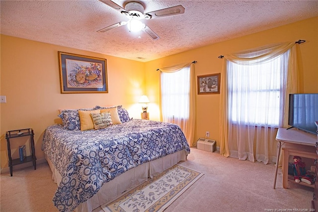 bedroom featuring ceiling fan, light carpet, multiple windows, and a textured ceiling