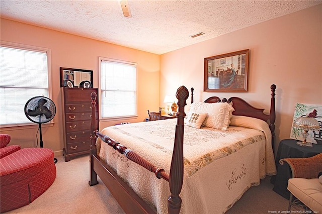 bedroom featuring ceiling fan, light colored carpet, and a textured ceiling