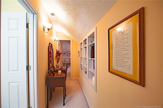 hall featuring light carpet, lofted ceiling, and a textured ceiling