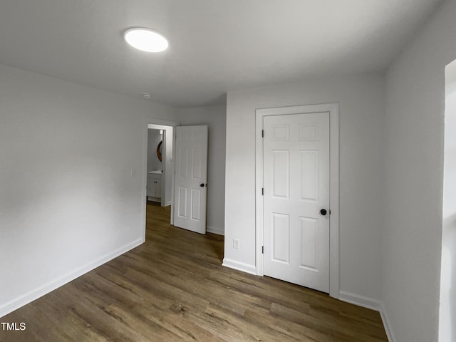 unfurnished bedroom with dark wood-type flooring and a closet