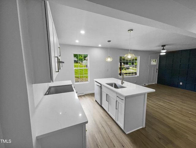 kitchen with sink, hanging light fixtures, light hardwood / wood-style floors, a center island with sink, and white cabinets