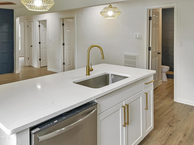 kitchen with light wood-type flooring, sink, decorative light fixtures, dishwasher, and white cabinetry