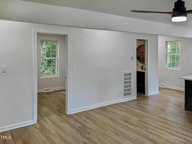 empty room featuring light hardwood / wood-style flooring, ceiling fan, and a healthy amount of sunlight