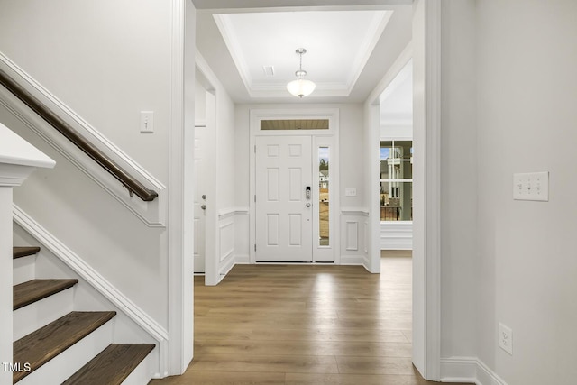 foyer with hardwood / wood-style flooring, crown molding, and a tray ceiling