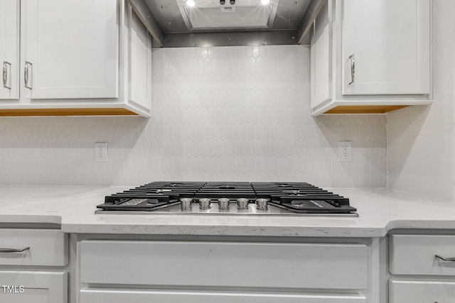 kitchen featuring light stone counters, white cabinetry, wall chimney exhaust hood, and stainless steel gas cooktop