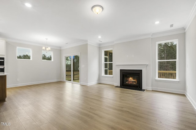 unfurnished living room with ornamental molding, a healthy amount of sunlight, an inviting chandelier, and light hardwood / wood-style flooring