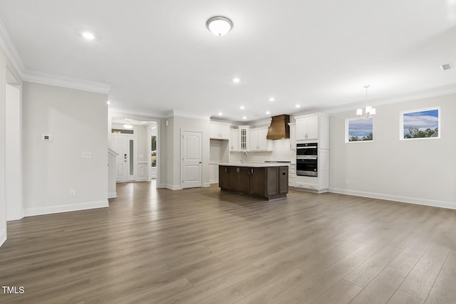 unfurnished living room with crown molding, an inviting chandelier, dark hardwood / wood-style flooring, and sink