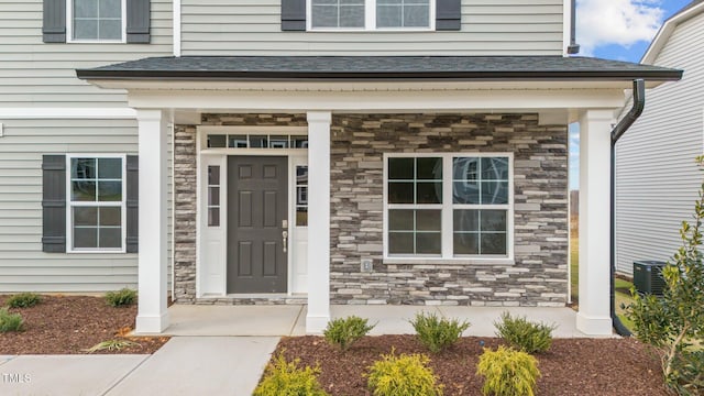 view of exterior entry featuring covered porch and cooling unit